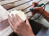 a teenager using a wood burning tool to create a design on a slab of raw wood