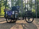 RPL's new book bike sits against a backdrop of trees and sunshine