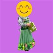 Young child holding a green book and wearing a dress made from green construction paper and a soda can box