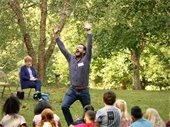 a storyteller makes a huge gesture with his arms as he tells a story to a group of children