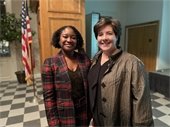 monica davis and melissa oleen stand side-by-side and smile for the camera in RPL headquarters' stanback auditorium 