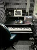 Podcast studio with a laptop, microphone, soundproofed walls, and other technology gear