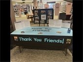 Display table featuring information about Friends of RPL in front of RPL Headquarters' spiral staircase