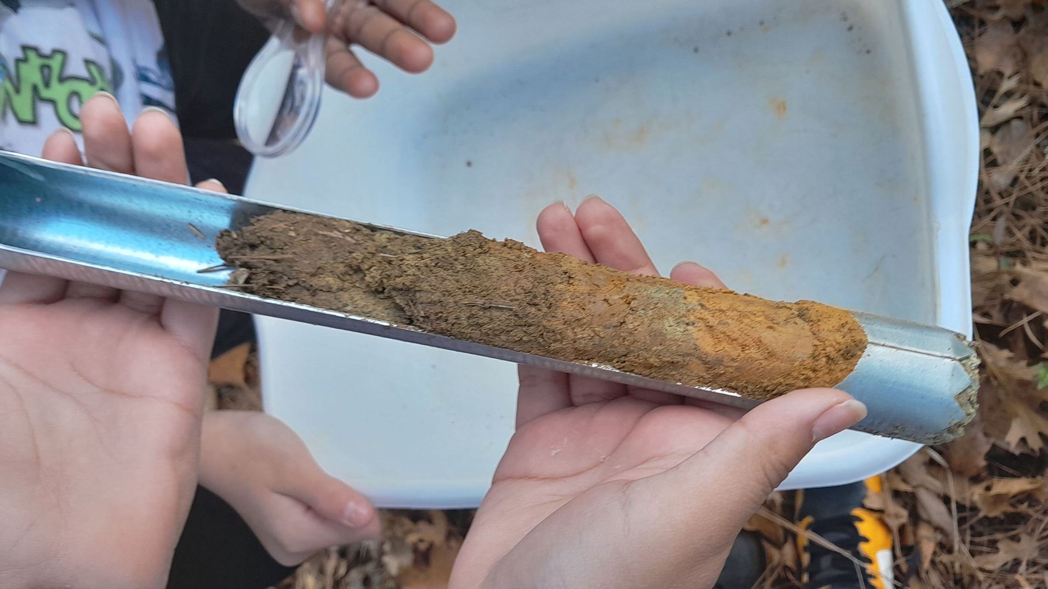 kids holding auger with soil