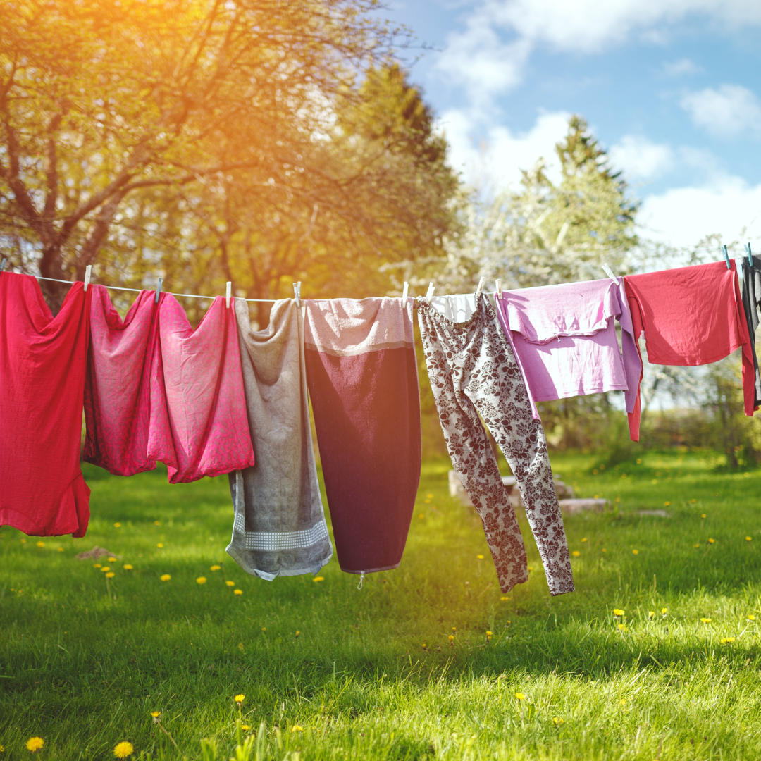 Laundry hanging on a clothes line in a yard at sunset.