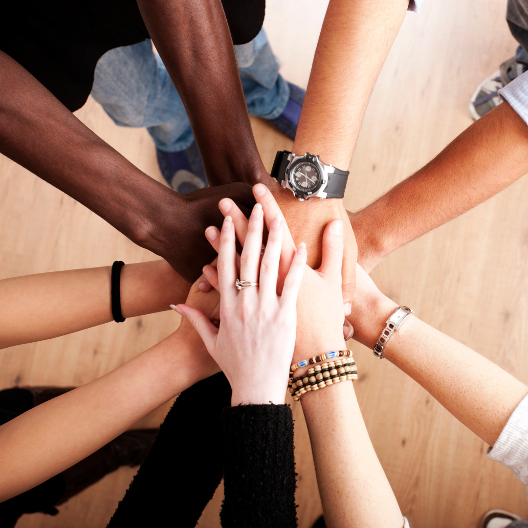 Racially diverse hands over top of each other in the center forming a sun shape.