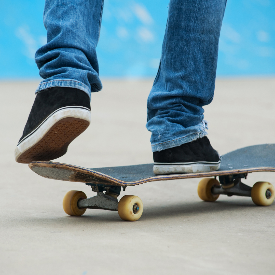 Silhouette of a teen male on a skateboard rolling away on a paved surface into the sunset.