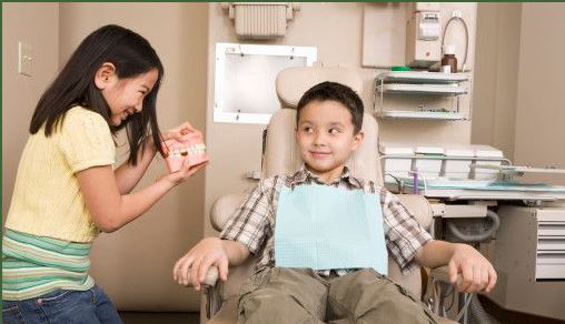 Boy in a dentist chair while a girl talks to him